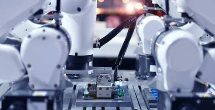 Close-up of collaborative robots (cobots) used for electronic component placement and quality control in modern automated production lines.