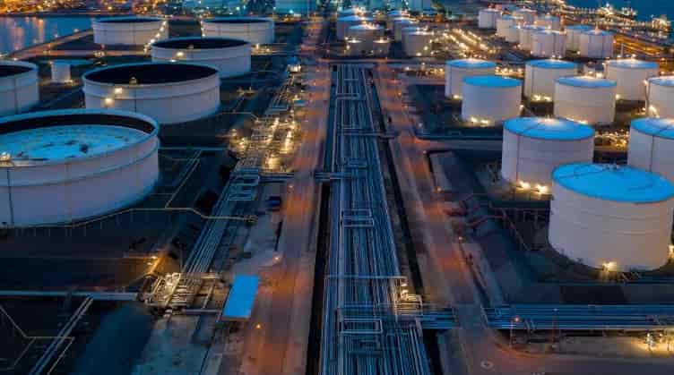 Petrochemical plant or oil refinery tank farm at dusk, showing bulk liquid storage and transport infrastructure.