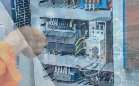Technician performing maintenance and troubleshooting inside an industrial electrical control panel.