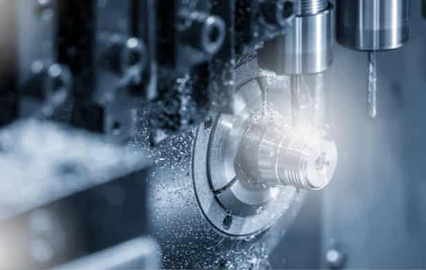Close-up of a CNC machine tool performing high-speed metal cutting and drilling on a precision part.