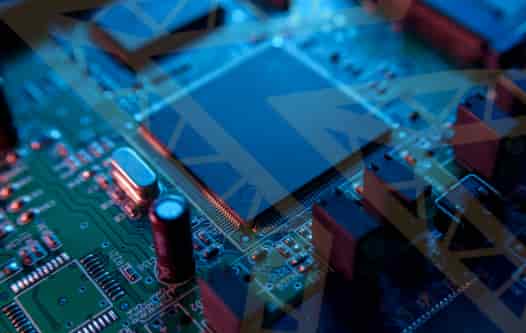 Close-up of a circuit board (PCB) with a microchip, overlaid with a UK flag, representing industrial electronics and components supply.